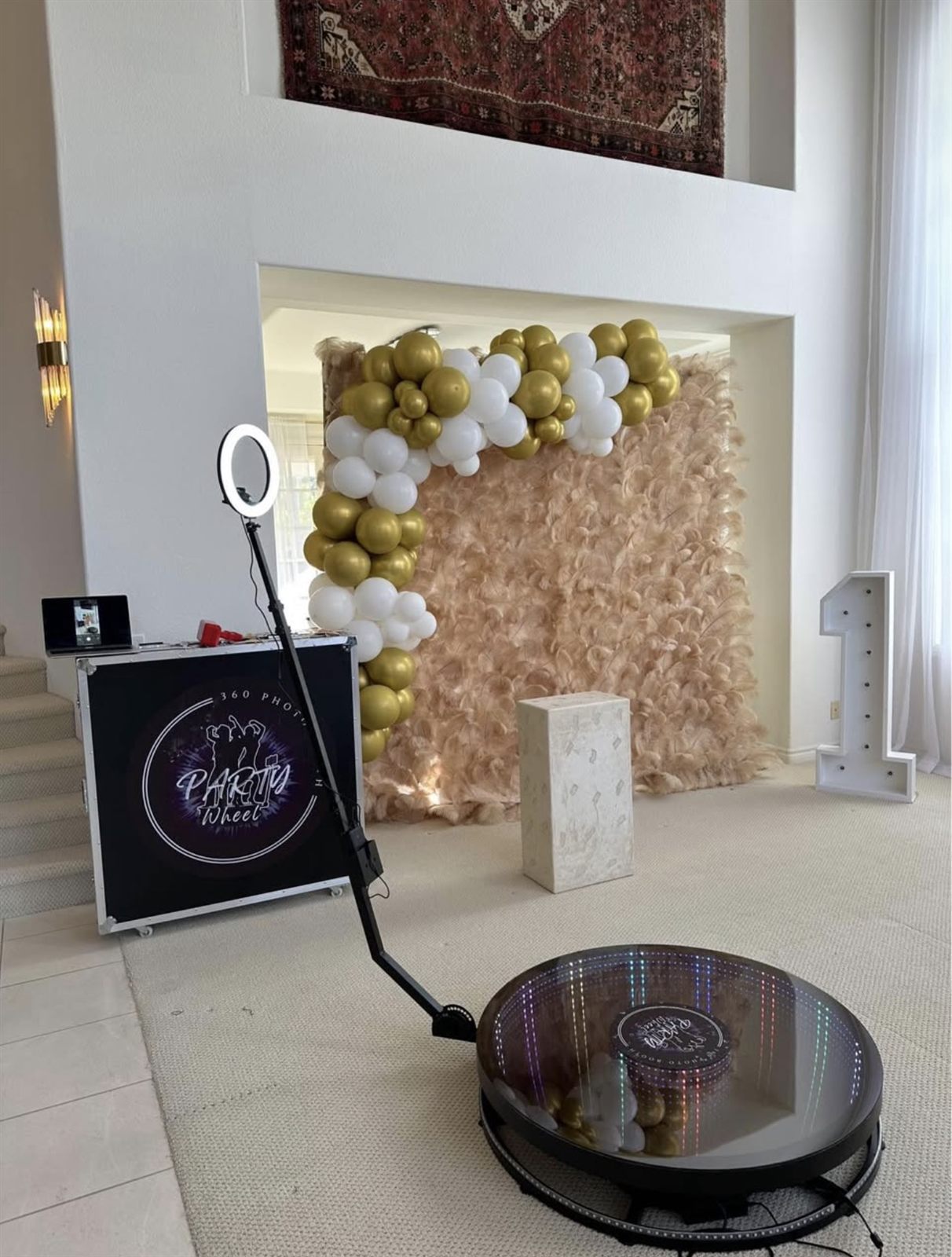 360 Party Wheel spin booth set up in front of a gold and white balloon arch