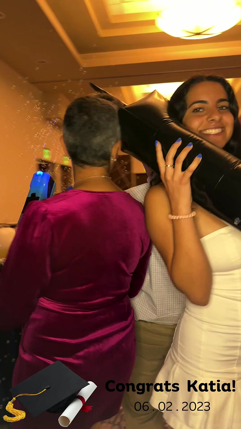 Graduation party guest holding a large black balloon, with a Congrats overlay