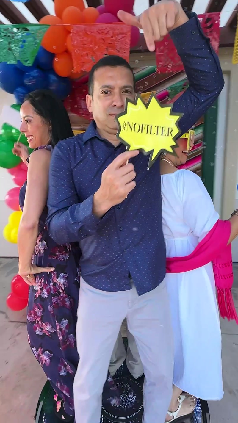 Man in a navy shirt holding a yellow #NOFILTER prop sign in front of the photo booth